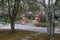 Two large exotic marble red dog statues surrounded by lush green trees near a long winding footpath in the garden