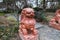 Two large exotic marble red dog statues surrounded by lush green trees near a long winding footpath in the garden