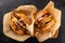 Two large grilled chicken burgers in a craft box on a dark background, top view.