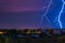 Two large and powerful lighting strikes crossing night blue sky