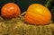 Two large ripe pumpkins on hay bale