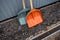 Two large shovels are waiting for the start of work on the gravel near the metal trailer.