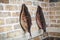 Two large smoked fish hanging on brick wall