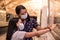 Two latin sisters pointing the poster on the train station wearing disposable mask to prevent coronavirus contagion