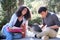 Two latin students smiling studying together sitting on a bench outdoors