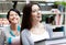 Two laughing girlfriends carry books