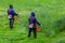 Two lawnmower men with string trimmer and face mask trimmong grass - close-up