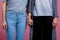 Two lesbians hold hands close-up on a pink background