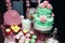 Two-leveled mint colored wedding cake with cream roses, macarons, and marshmallows. Candy Bar in pinky colors. Sweet