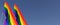 Two LGBT flags on a flagpole on a blue background on the side. The rainbow flag flutters in the wind. Place for text. LGBT
