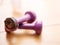 Two light small purple color dumbbell on a wooden floor. One has serious damage to plastic surface. Hard fitness workout concept.