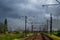 Two lines railway at the country side on the grey storm sky background. Electric poles at railroad.