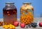 Two-litre cans with compote stand on a wooden surface. There`s a blue wall in the back. Homemade harvests from plums, apples,