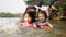 Two little Asian baby girls, sisters, enjoys playing water in a river with her auntie
