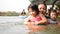 Two little Asian baby girls, sisters, enjoys playing water in a river with her auntie - playing outdoor and engaging with nature
