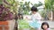 Two little Asian baby girls, sisters, harvesting young organic vegetables in a planting pot in front of their own house