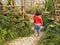 Two little Asian baby girls, sisters, walk on a walking path in a garden through beautiful plants and flowers