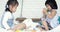 Two little asian cute girl playing colourful wood block on bed together .