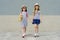 Two little beautiful girlfriends holding hands, girls walking in striped dresses, hats with backpack