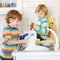 Two little blond kid boys washing dishes in domestic kitchen