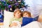 Two little blond sibling boys reading a book on Christmas