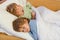 Two little blond sibling boys sleeping in bed