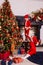 Two little boy in red costumes decorate the Christmas tree