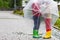 Two little boys, best friends and siblings walking with big umbrella outdoors on rainy day. Preschool children having