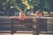 Two little boys brothers sit on wooden bench in park summer day