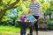 Two little boys having fun in wheelbarrow pushing by father