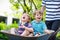 Two little boys having fun in wheelbarrow pushing by father