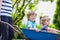 Two little boys having fun in a wheelbarrow pushing by father in