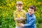 Two little boys hugging on the dandelion lawn