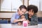 Two little boys putting money into piggy bank for future savings