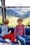 Two little boys sitting inside of cabin of cable car and looking on mountains landscape. Family on hiking vacations in