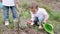 Two little brothers carrying cans for planting plants