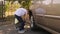 Two little brothers fix the wheels in the car, the boy uses a torque wrench.