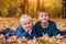 Two little brothers lying in yellow autumn leaves. Smiling and having fun. Fall day