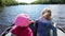 Two little Caucasian children sitting in motorboat during movement on forest lake. Close up