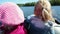 Two little Caucasian girls sailing in motorboat on forest lake. Close up