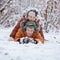 Two little children, boy brothers playing and lying in snow outdoors during snowfall. Active leisure with children in winter on co