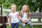 Two little children laugh and chat on a bench. Girls with backpacks. The concept is back to school, family, friendship and