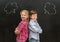 Two little children with phrase clouds on the blackboard