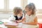 Two little classmate, laddie and girlie, are sitting at the same desk.