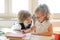 Two little classmate, laddie and girlie, are sitting at the same desk.