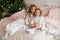 Two little curly-haired sisters are sitting on the bed in their nightgowns on the morning after Christmas