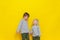 Two little cute boys hold hands and look at each other with a smile. Cheerful and mischievous children. Colored background.