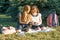 Two little girl friends schoolgirl learning sitting on a meadow in the park. Children with backpacks, books, notebooks