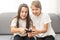 Two little girlfriends playing video game with joysticks. Excited and focused european children. Childhood concept