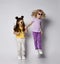 Two little girls blonde and brunette friends in stylish casual clothing and sunglasses play together jump holding hands